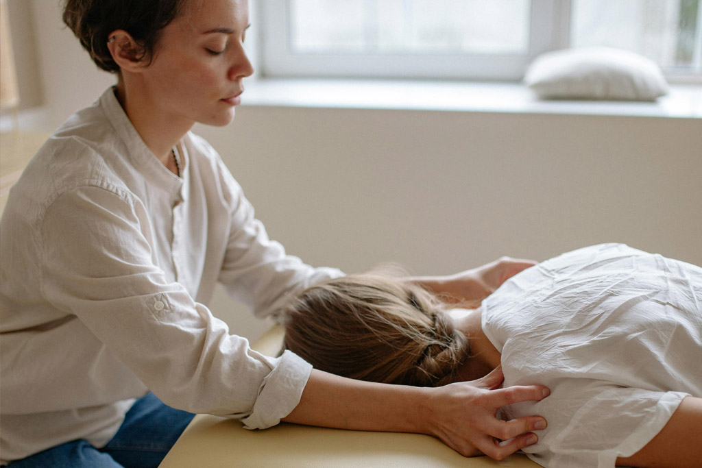 photo of woman giving massage to another woman